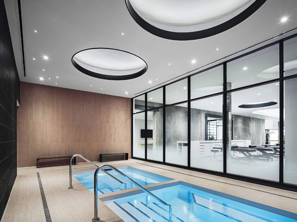 A swimming pool with a glass wall and a wooden floor.