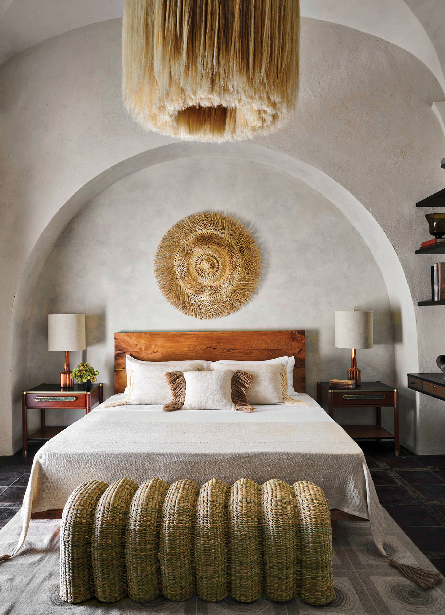 a bed with a large headboard and a large round light fixture