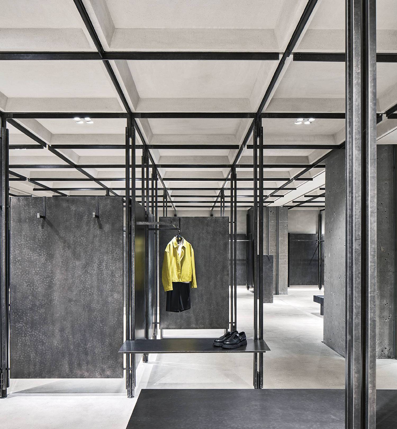 A yellow jacket hanging on a metal rack in a concrete room in ZARA