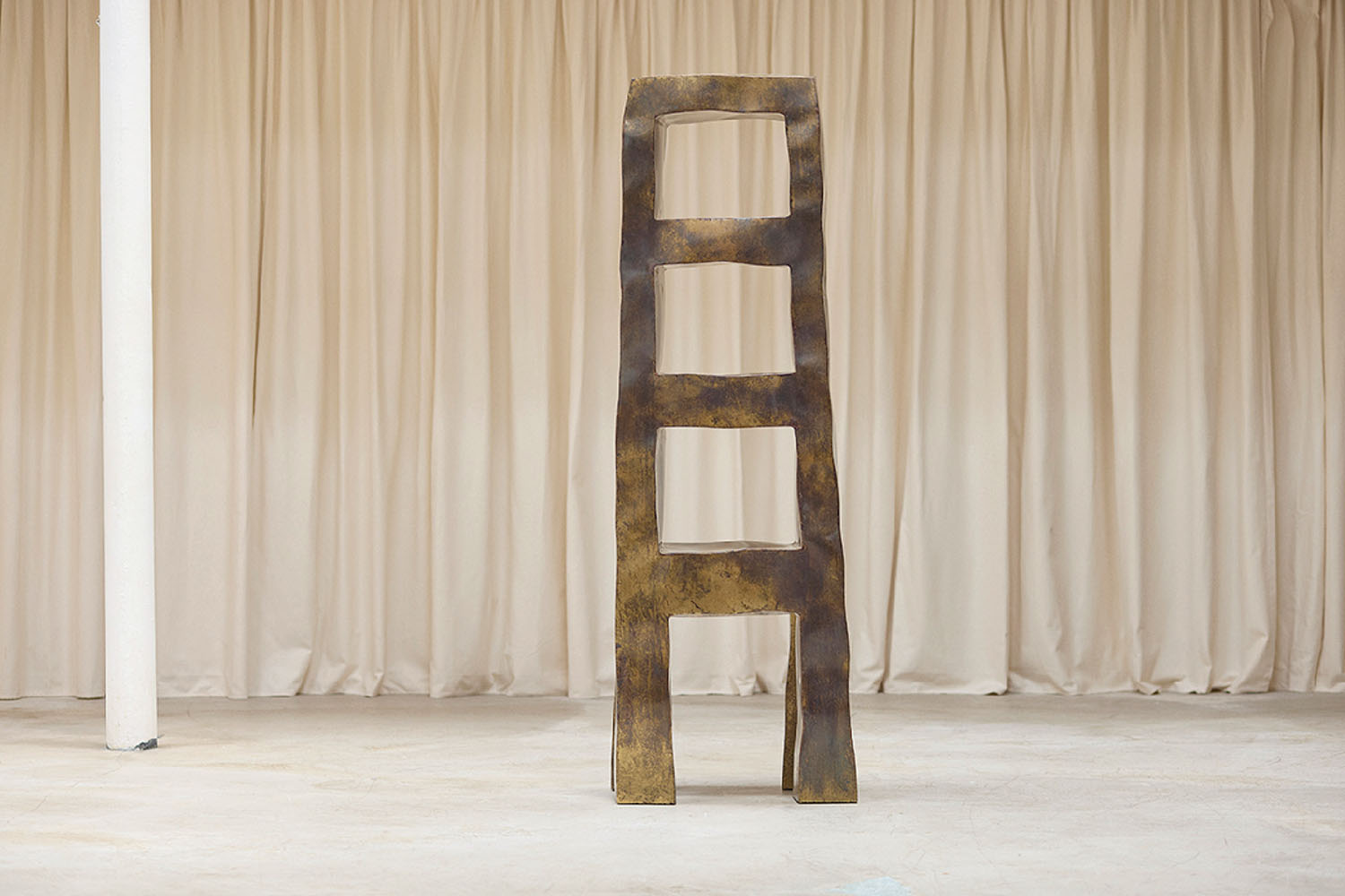 A tall metal sculpture sitting on top of a white floor