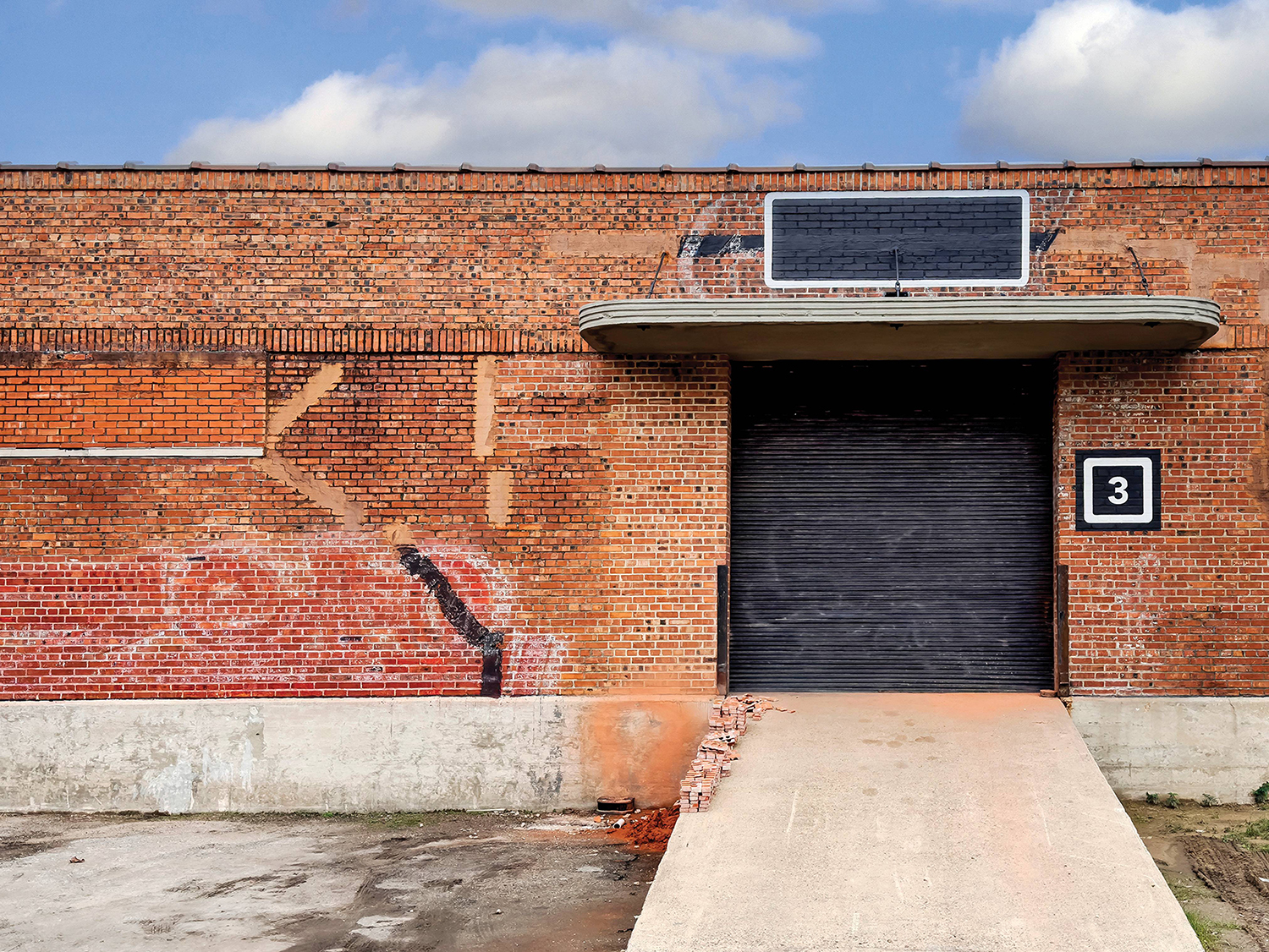 A brick building with a black door and a sign on the side