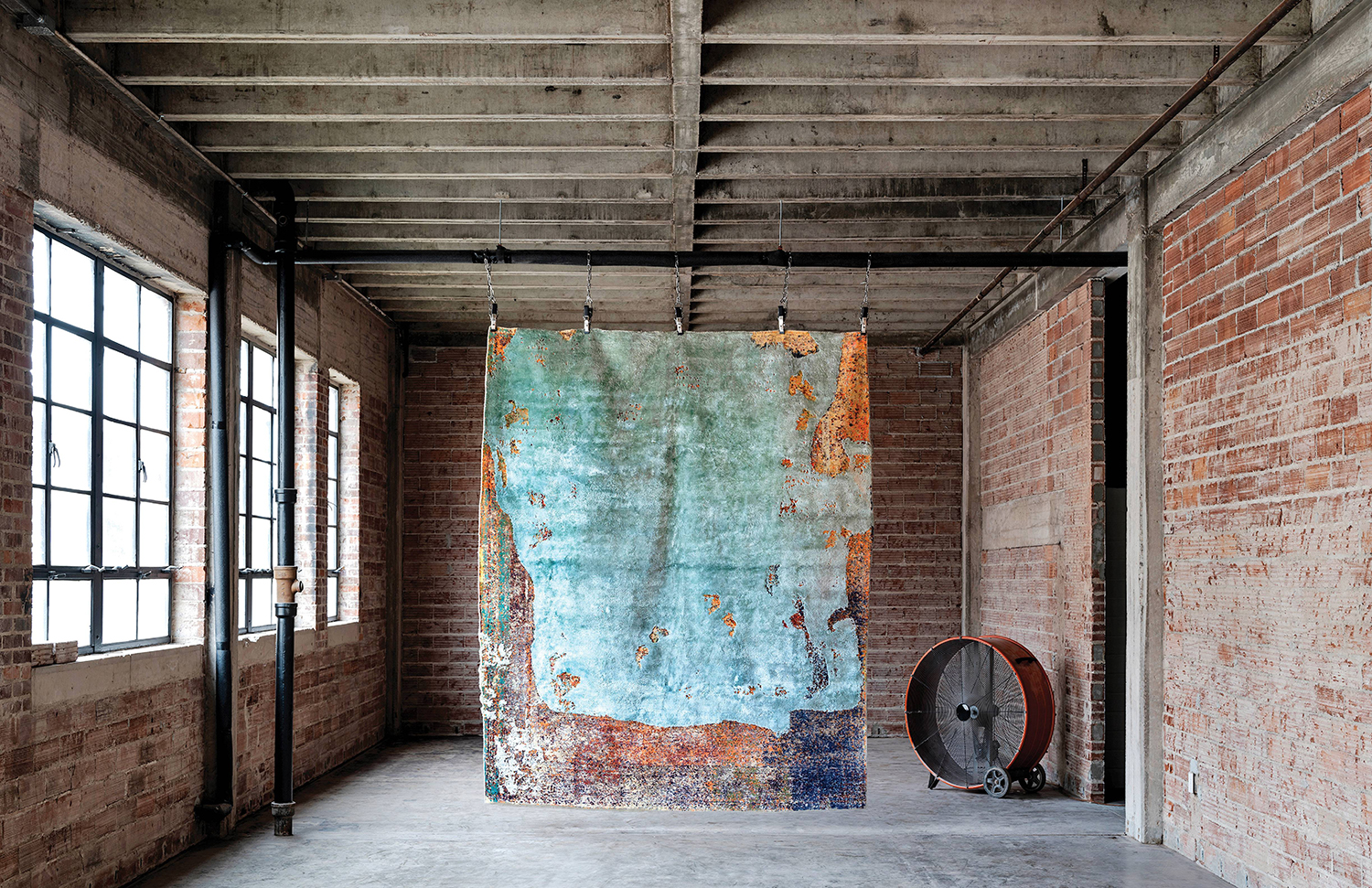 A large painting hanging on a brick wall