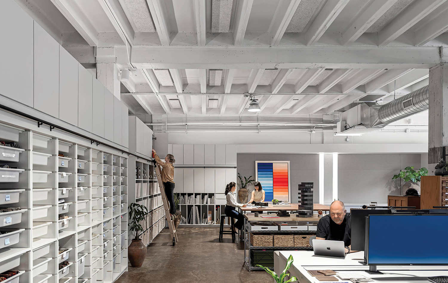A large open office with a long desk and a long wall of shelves