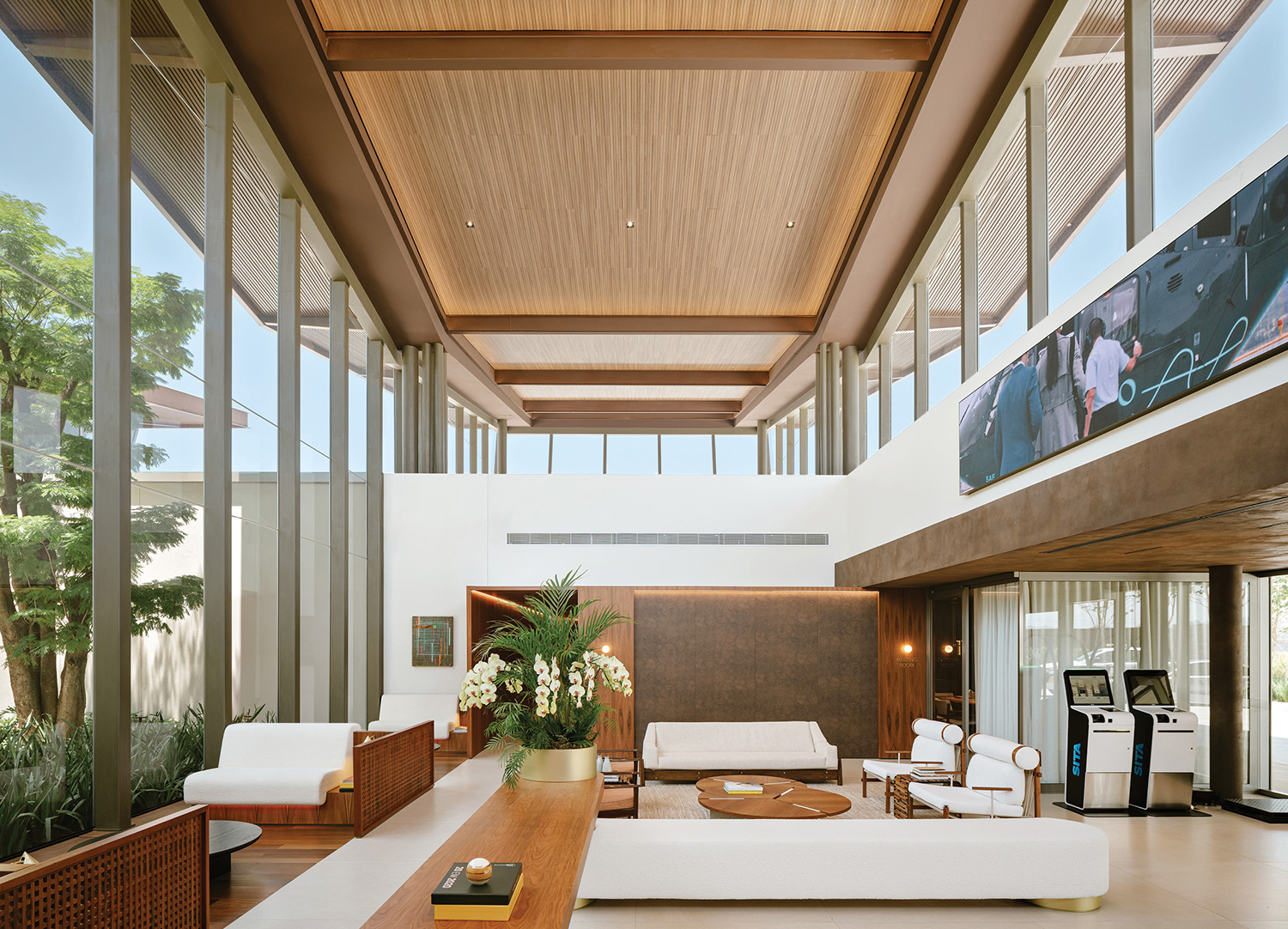 A living room with a large screen on the wall at the São Paulo Airport Terminal