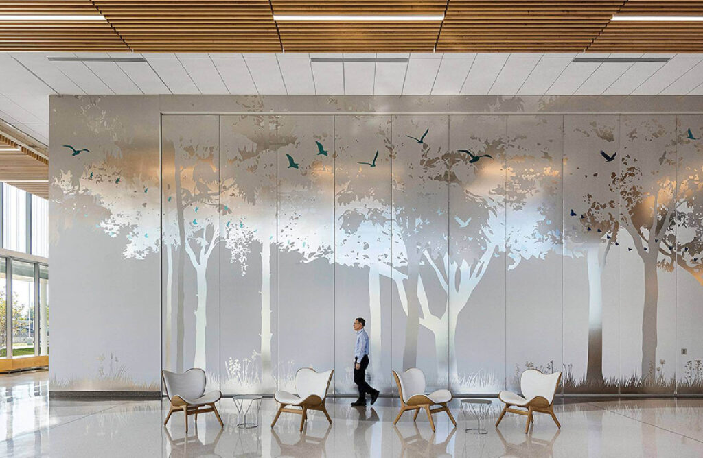 A man walking in a lobby with a mural of trees