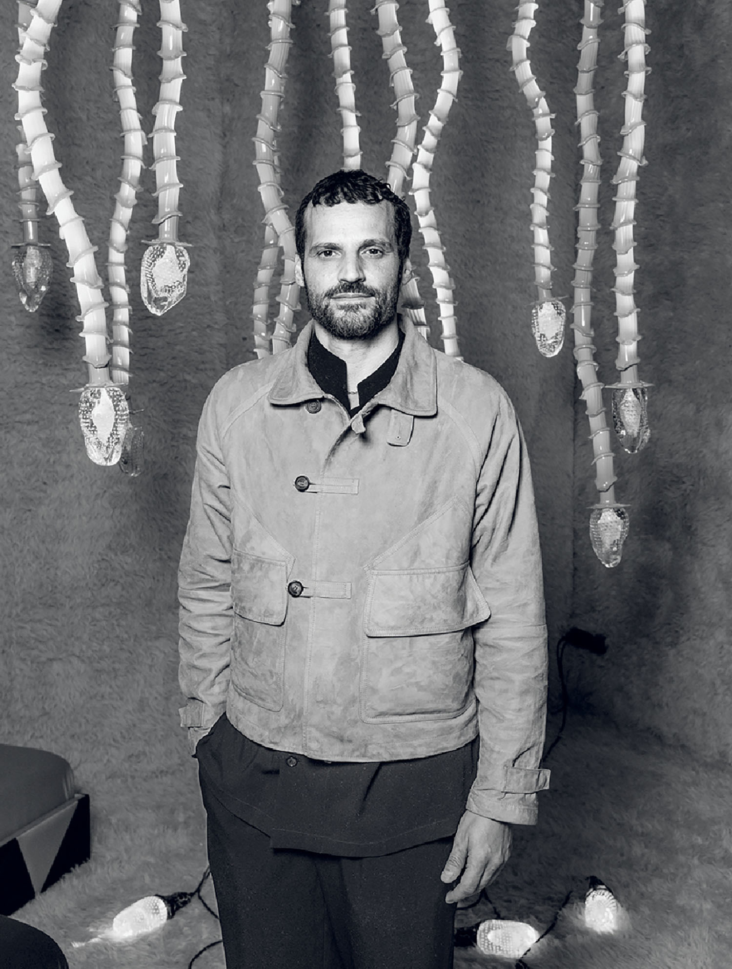 A man standing in front of a wall with many objects.